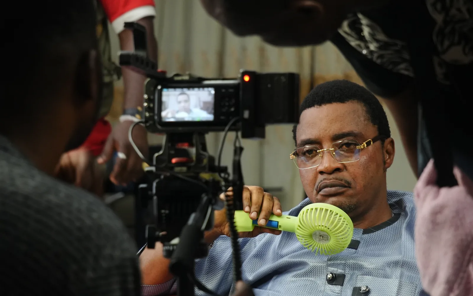 A film production set with a cameraman operating a camera while an actor performs and a director monitors the footage